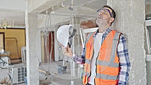 Middle age man builder tired taking out hardhat at construction site