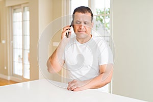 Middle age man calling using smartphone with a confident expression on smart face thinking serious