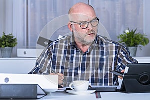 Middle age man checking his phone at his home office