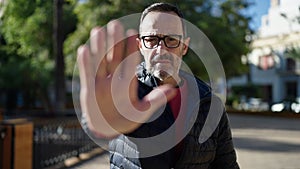 Middle age man doing stop gesture with hand at park