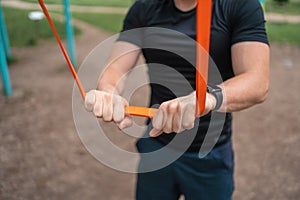 Middle age man doing strength exercises with resistance bands outdoors in park