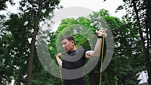 Middle age man doing strength exercises with resistance bands outdoors in park