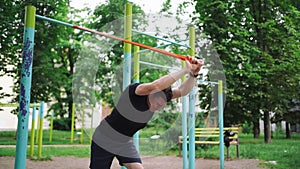 Middle age man doing strength exercises with resistance bands outdoors in park