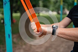 Middle age man doing strength exercises with resistance bands outdoors in park