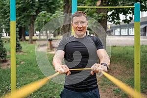 Middle age man doing strength exercises with resistance bands outdoors in park