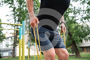 Middle age man doing strength exercises with resistance bands outdoors in park