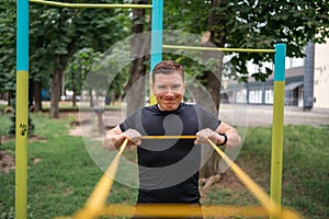 Middle age man doing strength exercises with resistance bands outdoors in park