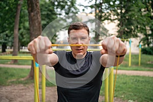 Middle age man doing strength exercises with resistance bands outdoors in park