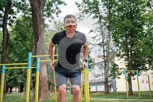 Middle age man doing strength exercises with resistance bands outdoors in park