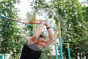 Middle age man doing strength exercises with resistance bands outdoors in park