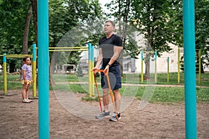 Middle age man doing strength exercises with resistance bands outdoors in park