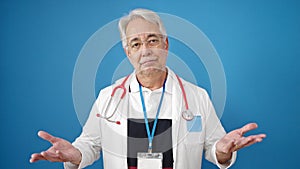 Middle age man with grey hair doctor standing clueless over isolated blue background