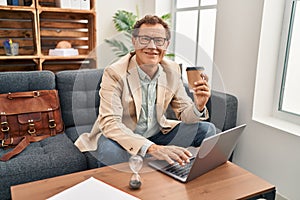 Middle age man having psychology session using laptop drinking coffee at clinic