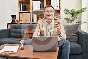 Middle age man having psychology session using laptop drinking coffee at clinic