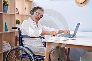 Middle age man having video call sitting on wheelchair teleworking at home