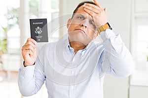 Middle age man holding holding passport of United States stressed with hand on head, shocked with shame and surprise face, angry