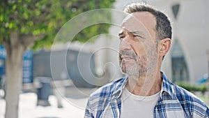 Middle age man looking to the side with serious expression at park