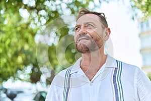 Middle age man looking to the sky with serious expression at park