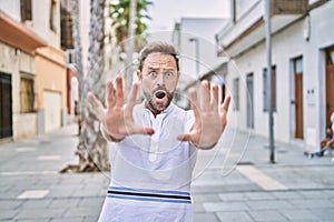 Middle age man outdoor at the city afraid and terrified with fear expression stop gesture with hands, shouting in shock