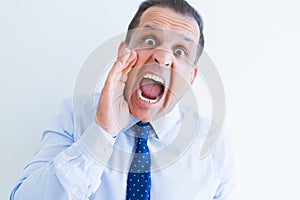 Middle age man shouting crazy with hands over mouth over white wall background