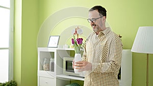 Middle age man smiling confident holding plant pot at home