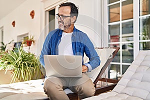Middle age man smiling confident using laptop at terrace home