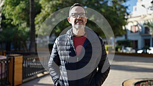 Middle age man standing with serious expression at park