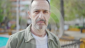 Middle age man standing with serious expression at park
