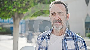 Middle age man standing with serious expression at park