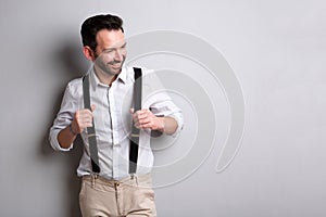 Middle age man with suspenders smiling against gray background