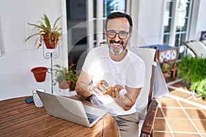 Middle age man using laptop taking pills at terrace home