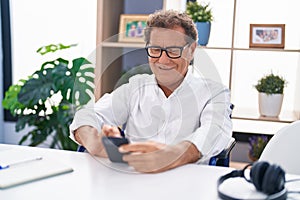 Middle age man using smartphone sitting on wheelchair teleworking at home