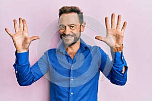 Middle age man wearing casual clothes showing and pointing up with fingers number ten while smiling confident and happy