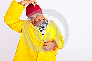 Middle age man wearing rain coat and woolen hat standing over isolated white background confuse and wonder about question