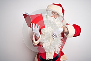 Middle age man wearing Santa Claus costume reading book over isolated white background Looking at the watch time worried, afraid