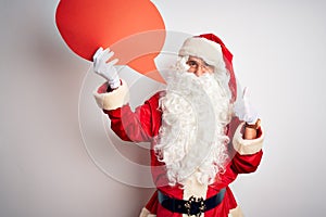 Middle age man wearing Santa costume holding speech bubble over isolated white background happy with big smile doing ok sign,