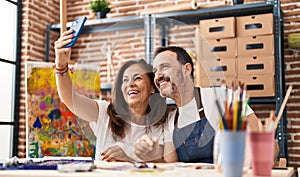 Middle age man and woman artists drawing on notebook make selfie by the smartphone at art studio