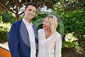 Middle age man and woman couple hugging each other standing at park