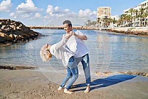 Middle age man and woman couple smiling confident dancing at seaside