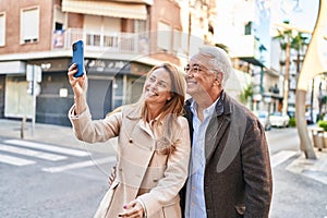 Middle age man and woman couple smiling confident making selfie by the smartphone at street