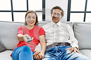 Middle age man and woman couple smiling confident watching tv at home