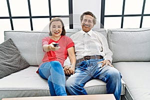 Middle age man and woman couple smiling confident watching tv at home