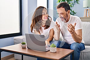 Middle age man and woman couple using laptop sitting on sofa at home