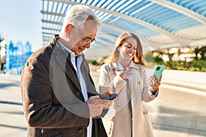 Middle age man and woman couple using smartphone drinking coffee at park