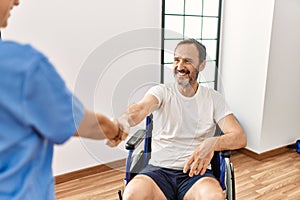 Middle age man and woman smiling confident having physiotherapy session shake hands at physiotherapy clinic