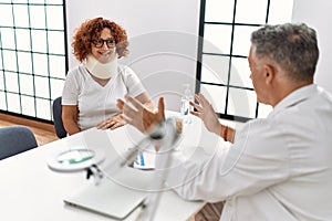 Middle age man and woman wearing doctor uniform having medical consultation for accident at clinic