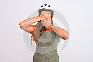 Middle age mature cyclist woman wearing safety helmet over isolated background Covering eyes and mouth with hands, surprised and