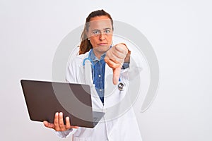 Middle age mature doctor woman holding computer laptop over isolated background with angry face, negative sign showing dislike