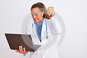 Middle age mature doctor woman holding computer laptop over isolated background annoyed and frustrated shouting with anger, crazy