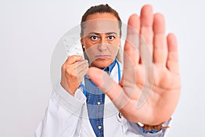 Middle age mature doctor woman showing prescription pills over isolated background with open hand doing stop sign with serious and